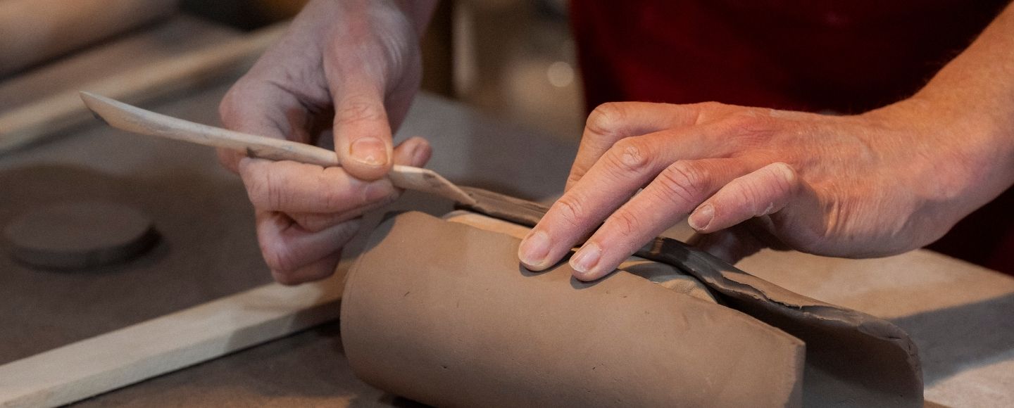 Manos trabajando la arcilla con las herramientas en el Atelier de Esther en Balmori, Llanes, Asturias